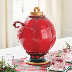 a large red pot sitting on top of a table next to glasses and utensils