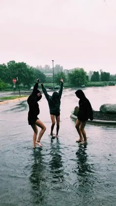 three people standing in the middle of a flooded street with their hands up and arms raised