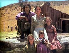 an image of a family posing in front of a log cabin with the caption's name on it