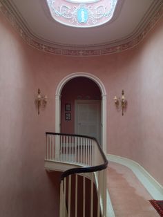 a staircase in a pink room with a skylight on the ceiling and chandelier above it