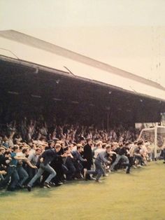 a group of people standing on top of a field next to a soccer goal in front of a crowd