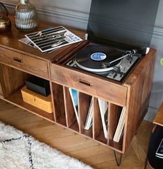 a record player sitting on top of a wooden cabinet next to a table with records