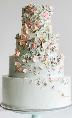 a three tiered white cake with pink flowers on top