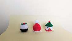 three small knitted christmas hats sitting on top of a white table next to each other