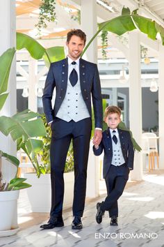 a man in a suit and tie walking next to a little boy wearing a tuxedo