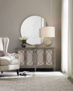 a living room with a chair, mirror and lamp on the side table in front of it