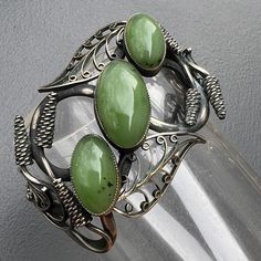 Fabulous ~ WIDE ~  Vintage  Art nouveau style oxidized sterling silver plated ~ handmade cuff bracelet with a large bezel set green  stone in center with applied leaf design around on openwork background  ~ Beautiful details all around . Unmarked  Dates : unknow but most likely mid to late 20th century  Measurements : bangle is 5 1/4  inches in inner length  x 1 1/2 inches max width  . Gap between two ends is  1 1/2 inches . Can be adjusted a bit according to your wrist size .  Weighs 33 grams on my weighing scale. Condition :  Overall in good vintage condition with heavy age patina  ~ some surface wear to metal  and stones .  Please Note ~ As vintage items are previously loved /used please do expect some minor wear like surface wear /dents /dings and metal discoloration . All items are ca Cuff Bracelets Handmade, Background Beautiful, Art Nouveau Style, Antique Necklace, Bracelet Sterling Silver, Silver Plated Jewelry, Sterling Silver Hoop Earrings, Oxidized Sterling Silver, Sterling Silver Hoops