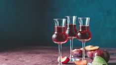 three glasses filled with red wine and fruit