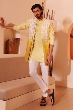 Ombre yellow padma silk jacket with ogee pattern, floral embroidered jacket in beads, cutdana work. Paired with an inner kurta and pant.
Components: 3
Pattern: Embroidered Jacket
Type Of Work: Floral, Beads
Neckline: Stand Collar
Sleeve Type: Full Sleeves
Fabric: Padma Silk
Color: Yellow
Other Details: 
Loop lace on jacket
Loop buttons on kurta
Note: The kurta set worn by the model on the left is not for sale
Occasion: Sangeet - Aza Fashions Haldi Men Outfit Groom, Mens Mehndi Outfit, Embroidered Chinon Sherwani For Festive Occasions, Festive Embroidered Sherwani In Chinon, Festive Embroidered Chinon Sherwani, Designer Sherwani For Diwali In Chinon, Bollywood Style Outerwear With Chikankari Embroidery, Festival Chanderi Bandhgala With Dupatta, Festival Bandhgala With Dupatta In Chanderi Fabric