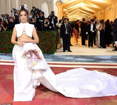 a woman in a white gown is standing on the red carpet with cameras around her