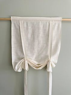 a white curtain hanging on the side of a wall with two ties attached to it