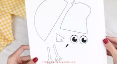 a person holding up a paper cut out of a cartoon character with eyes and ears