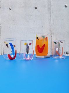 four different colored glasses sitting on top of a blue table