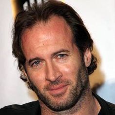 a close up of a person wearing a black shirt and smiling at the camera with an intense look on his face