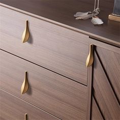 a close up of a wooden dresser with brass handles