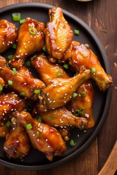 chicken wings with sesame seeds and garnishes on a black plate, ready to be eaten