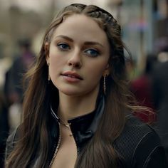 a woman with long hair wearing a black leather jacket and gold chains on her neck