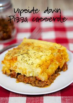 a white plate topped with lasagna next to a red and white checkered table cloth