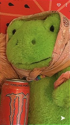 a green stuffed animal with a red can