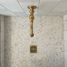 a gold faucet mounted to the side of a white tiled wall