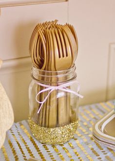 a jar filled with gold colored utensils on top of a table