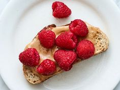 a piece of bread with raspberries on top and peanut butter on the side