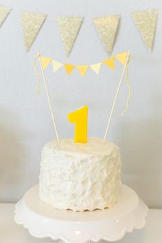 a white cake topped with a yellow number one candle