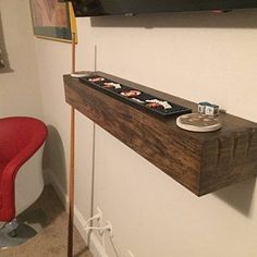 a red chair sitting next to a wooden shelf with sushi on it's side