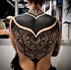 the back of a woman's body with an intricate tattoo design on her shoulder