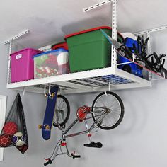 a bicycle hanging on the wall next to some storage bins and other items in a room