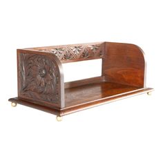 a wooden shelf with carved designs on the front and sides, sitting against a white background