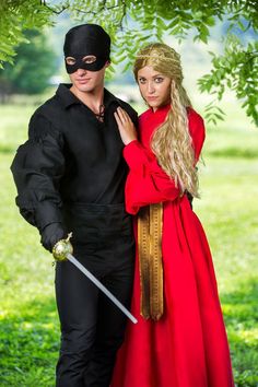 a man and woman dressed up in costume standing next to each other under a tree