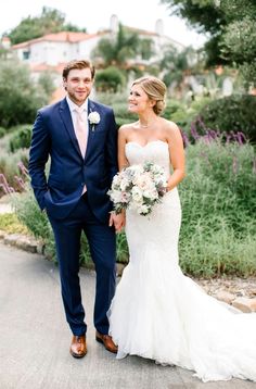 a bride and groom are walking down the street in front of some lavender bushes at their wedding