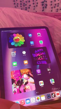 an ipad sitting on top of a bed next to a pink comforter and pillows