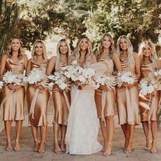 a group of women in gold dresses standing next to each other with flowers on their bouquets