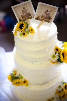 a wedding cake with sunflowers and two photos on top