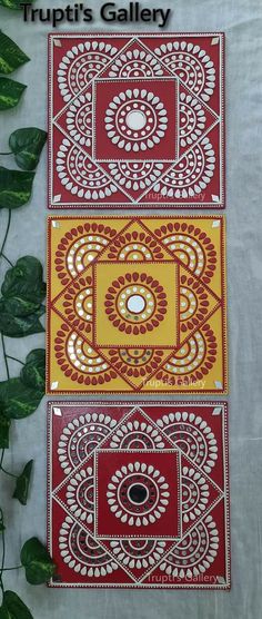 three red and yellow paintings on white paper with green leaves in the foreground, one is