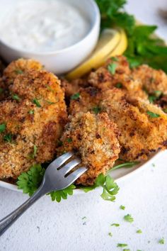 two crab cakes on a plate with lemon wedges, parsley and sour cream