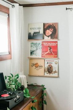 a record player sitting on top of a wooden table next to a window with white curtains