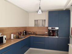 a kitchen with blue and white cabinets and counter tops, an oven, microwave and toaster