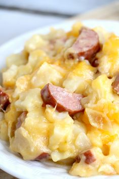 a white plate topped with ham and cheese casserole on top of a wooden table