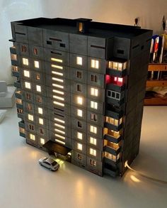 a model of a building with cars parked in front of it and windows lit up at night