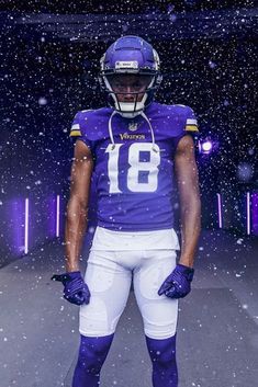 a football player standing in the snow with his helmet and gloves on, wearing a purple uniform