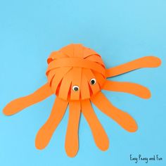 an orange paper octopus with googly eyes on a blue background, cut out from construction paper