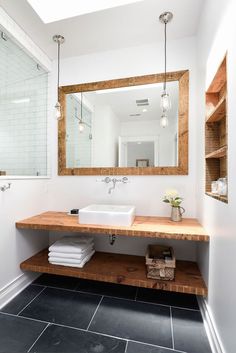 a bathroom sink sitting under a mirror next to a shelf with folded towels on it