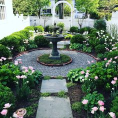 a garden with flowers and a fountain in the center, surrounded by greenery on both sides