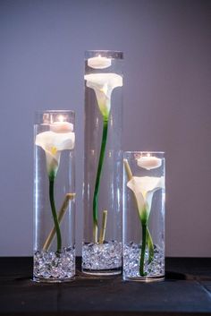 three glass vases with flowers in them on a table