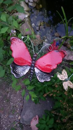 a red butterfly statue sitting on top of a lush green field