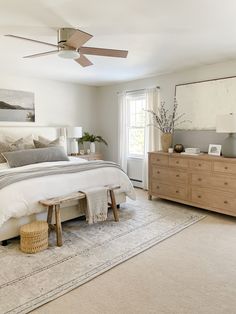 a bed room with a neatly made bed and a ceiling fan in the middle of it