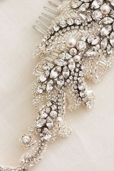 a bridal hair comb is adorned with crystal and pearled beads on a white cloth